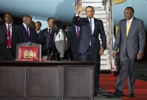 President Barack Obama waves as he walks with Kenyan President Uhuru Kenyatta to sign a guest book after arriving at Kenyatta International Airport, on Friday, July 24, 2015, in Nairobi, Kenya. Obama's link to Kenya, where he began his first visit as U.S. president, is a father he barely knew but whose influence can nonetheless be seen in his son's presidency. (AP Photo/Evan Vucci)