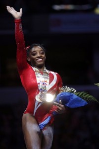 Simone Biles waives to the crowd after being winning the all-around competition at the U.S. women's gymnastic championships Saturday, Aug. 15, 2015, in Indianapolis. (AP Photo/AJ Mast)