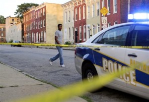In this July 30, 2015 picture, a man walks past a corner where a victim of a shooting was discovered in Baltimore. Murders are spiking again in Baltimore, three months after Freddie Grays death in police custody sparked riots. This years monthly bloodshed has twice reached levels unseen in a quarter-century. In May, Baltimore set a 25-year high of 42 recorded killings. After a brief dip in June, the homicide is soaring again. (AP Photo/Patrick Semansky)