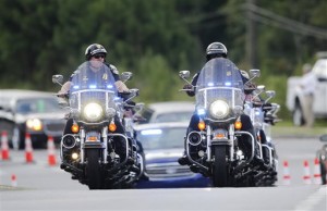 Police officers on motorcycles led a procession of mourners to a funeral for Bobbi Kristina Brown Saturday, Aug. 1, 2015, in Alpharetta, Ga. Brown, the only child of Whitney Houston and R&B singer Bobby Brown, died in hospice care July 26, about six months after she was found face-down and unresponsive in a bathtub in her suburban Atlanta townhome. (AP Photo/John Bazemore)