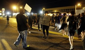 Crowds chant in the street along West Florissant Avenue, Monday, Aug. 10, 2015, in Ferguson, Mo. Ferguson was a community on edge again Monday, a day after a protest marking the anniversary of Michael Brown's death was punctuated with gunshots. (AP Photo/Jeff Roberson)