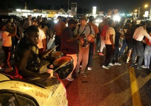 Protesters gather along West Florissant Avenue during a demonstration in Ferguson, Mo., Tuesday, Aug. 11, 2015. The St. Louis suburb has seen demonstrations for days marking the anniversary of the death of 18-year-old Michael Brown, whose shooting death by a Ferguson police officer sparked a national "Black Lives Matter" movement. Tuesday was the fifth consecutive night a crowd gathered on West Florissant, the thoroughfare that was the site of massive protests and rioting after Brown was killed.  (AP Photo/Jeff Roberson)