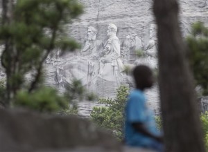 In this Tuesday, June 23, 2015, file photo, a youngster plays on a rock in front of the carving on Stone Mountain, in Stone Mountain, Ga. The carving depicts confederates Robert E. Lee, Jefferson Davis and Stonewall Jackson. Planning is underway to place a replica of the Liberty Bell atop Stone Mountain as a memorial to the Rev. Martin Luther King Jr. that recalls a famous line from his I Have a Dream speech, officials say. (AP Photo/John Bazemore, File)