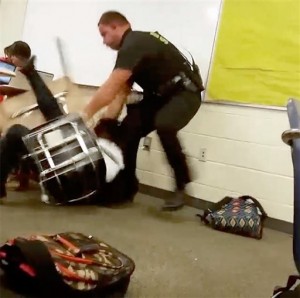 In this Monday, Oct, 26, 2015 photo made from video taken by a Spring Valley High School student, Senior Deputy Ben Fields tries to forcibly remove a student who refused to leave her high school math class, in Columbia S.C. The Justice Department opened a civil rights investigation Tuesday after Fields flipped the student backward in her desk and tossed her across the floor. (AP Photo)