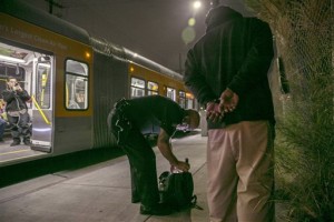 In this Tuesday, Oct. 27, 2015, photo, Los Angeles Police Department Officer Greg Smith searches the bag of a bus passenger who matched the description of a suspected thief riding the bus in South Los Angeles. The man was searched and released without incident. The LAPD has deployed hundreds of elite officers to crime hot spots, increased the number of officers walking the streets versus patrolling in cars, and created a community relationship division dedicated to building the public's trust in police officers. (AP Photo/Damian Dovarganes)