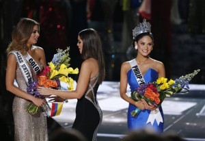 Former Miss Universe Paulina Vega, center, takes away the flowers and sash from Miss Colombia Ariadna Gutierrez, left, before giving it to Miss Philippines Pia Alonzo Wurtzbach, right, at the Miss Universe pageant Sunday, Dec. 20, 2015, in Las Vegas. According to the pageant, a misreading led the announcer to read Miss Colombia Ariadna Gutierrez as the winner before they took it away and gave it to Miss Philippines.(AP Photo/John Locher)