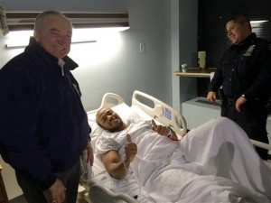 In this photo provided by the New York Police Department, Officer Sherrod Stuart, center, poses with New York City Police Commissioner William Bratton, left, Saturday, Jan. 9, 2016, in New York. Stuart was shot in the ankle early Saturday during an exchange of gunfire with a suspect involved in a large fight, authorities said. (NYPD via AP)