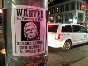 In this photo taken on Wednesday, Jan. 27, 2016, a poster offering a $5,000 reward for "citizen arrest" of Michigan Gov. Rick Snyder is displayed in downtown Ann Arbor, Mich. The posters were among messages criticizing Snyder, including ones written in chalk on sidewalks, over his handling of the water crisis in Flint, Michigan. (Ryan Stanton /The Ann Arbor News via AP) LOCAL TELEVISION OUT; LOCAL INTERNET OUT; MANDATORY CREDIT