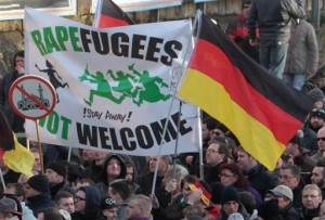 Right-wing demonstrators hold a sign "Rapefugees not welcome - !Stay away!" and a sign with a crossed out mosque as they march in Cologne, Germany Saturday Jan. 9, 2016. Womens rights activists, far-right demonstrators and left-wing counter-protesters all took to the streets of Cologne on Saturday in the aftermath of a string of New Years Eve sexual assaults and robberies in Cologne blamed largely on foreigners. (AP Photo/Juergen Schwarz)