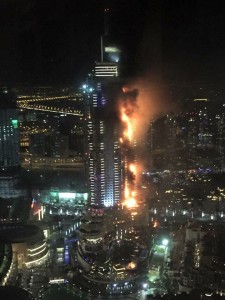 In this photo provided by Trevor Hale, smoke and flames pour out from a residential building as a fire runs up some 20 stories of the high rise in Dubai, United Arab Emirates, Thursday, Dec. 31, 2015. Fire engulfed the luxury building near the world's tallest skyscraper in Dubai on Thursday as tens of thousands of people were gathering at its base for one of the world's largest New Year's fireworks displays. (Trevor Hale via AP)