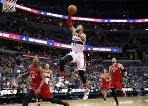 Washington Wizards guard Garrett Temple (17) goes up for a dunk between Toronto Raptors guard DeMar DeRozan (10) and center Jonas Valanciunas (17) during the second half of an NBA basketball game Friday, Jan. 8, 2016, in Washington. The Raptors won 97-88. (AP Photo/Alex Brandon)