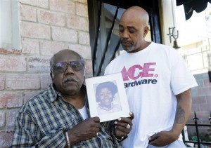 In this Feb. 8, 2016 photo, Porter Alexander, with his son Donnell Alexander, holds a photo of his daughter, an alleged victim of the "Grim Sleeper" serial killer, at his home in Los Angeles. More than 30 years since the bodies of young women started turning up in alleyways and garbage bins in south Los Angeles, attorneys are set to give opening statements Tuesday, Feb. 16, 2016, in the long-awaited Grim Sleeper trial. Lonnie David Franklin Jr. has pleaded not guilty to killing nine women and a 15-year-old girl from 1985 to 2007 in one of the citys most notorious serial killer cases. (AP Photo/Nick Ut)