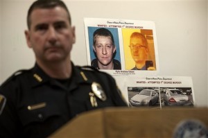 Coeur d'Alene Police Chief Lee White speaks during a news conference Monday, March 7, 2016, with a photo of Kyle Andrew Odom in the background in Coeur D'Alene, Idaho.  An Idaho pastor who led the prayer at a weekend campaign rally for Republican presidential candidate Ted Cruz was gunned down outside his church the following day but was expected to survive. The Coeur d'Alene Police Department said it is looking for local resident Odom, 30, a decorated former Marine who should be considered armed and dangerous. (Kathy Plonka/The Spokesman-Review, via AP)