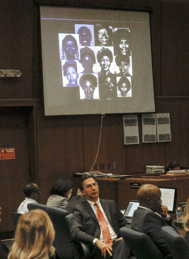 In this May 2, 2016 file photo, a montage of photos of alleged victims is projected on a screen in the courtroom during the during closing arguments in the serial murder trial of Lonnie Franklin Jr., seated at far left, in Los Angeles Superior Court. Franklin was convicted Thursday, May 5, 2016, of 10 murders and one attempted murder in the serial killings that were dubbed the work of the Grim Sleeper because of a 14-year gap in slayings that spanned two decades in South Los Angeles and targeted vulnerable young black women in the inner city. (Mark Boster/ Los Angeles Times, Pool, File)