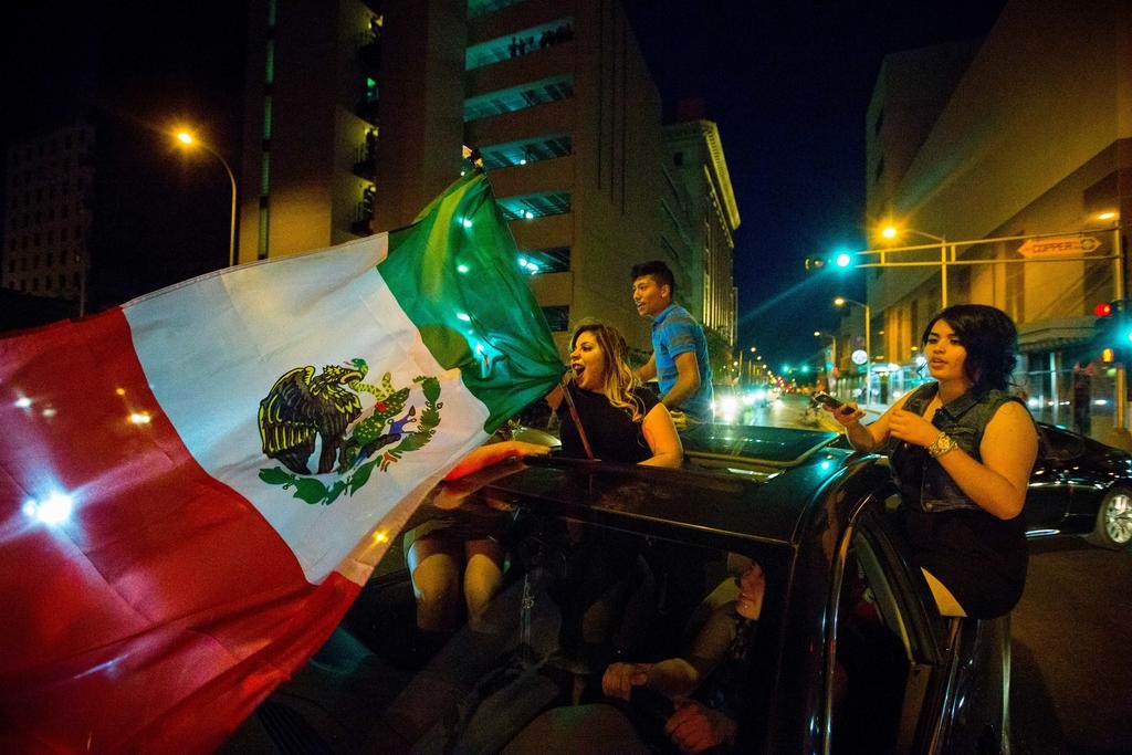 In this May 24, 2016, photo, a woman waves the Mexican flag while driving past the Albuquerque Convention Center after a rally by Republican presidential candidate Donald Trump in Albuquerque, N.M. Hispanic voters in Florida, New Mexico and California have waved Mexican flags and bashed Donald Trump piñatas to protest the Republican presidential contenders hard line approach to immigration. Yet far from the protests, an increasingly vocal Hispanic minority is speaking out in favor of the brash billionaire.  (Jett Loe/The Las Cruces Sun-News via AP) MANDATORY