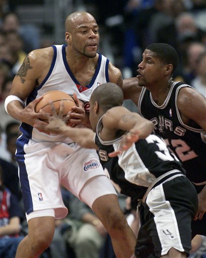 In this  Saturday, April 7, 2001 file photo, Los Angeles Clippers' Sean Rooks fends off San Antonio Spurs defenders Antonio Daniels and Samaki Walker, right, during the first half of a basketball game in Los Angeles. Former NBA center and Philadelphia 76ers assistant coach Sean Rooks has died. He was 46. The team released a statement from Deborah Brown, the mother of Rooks, on Tuesday night, June 7, 2016. (AP Photo/Jill Connelly, File)